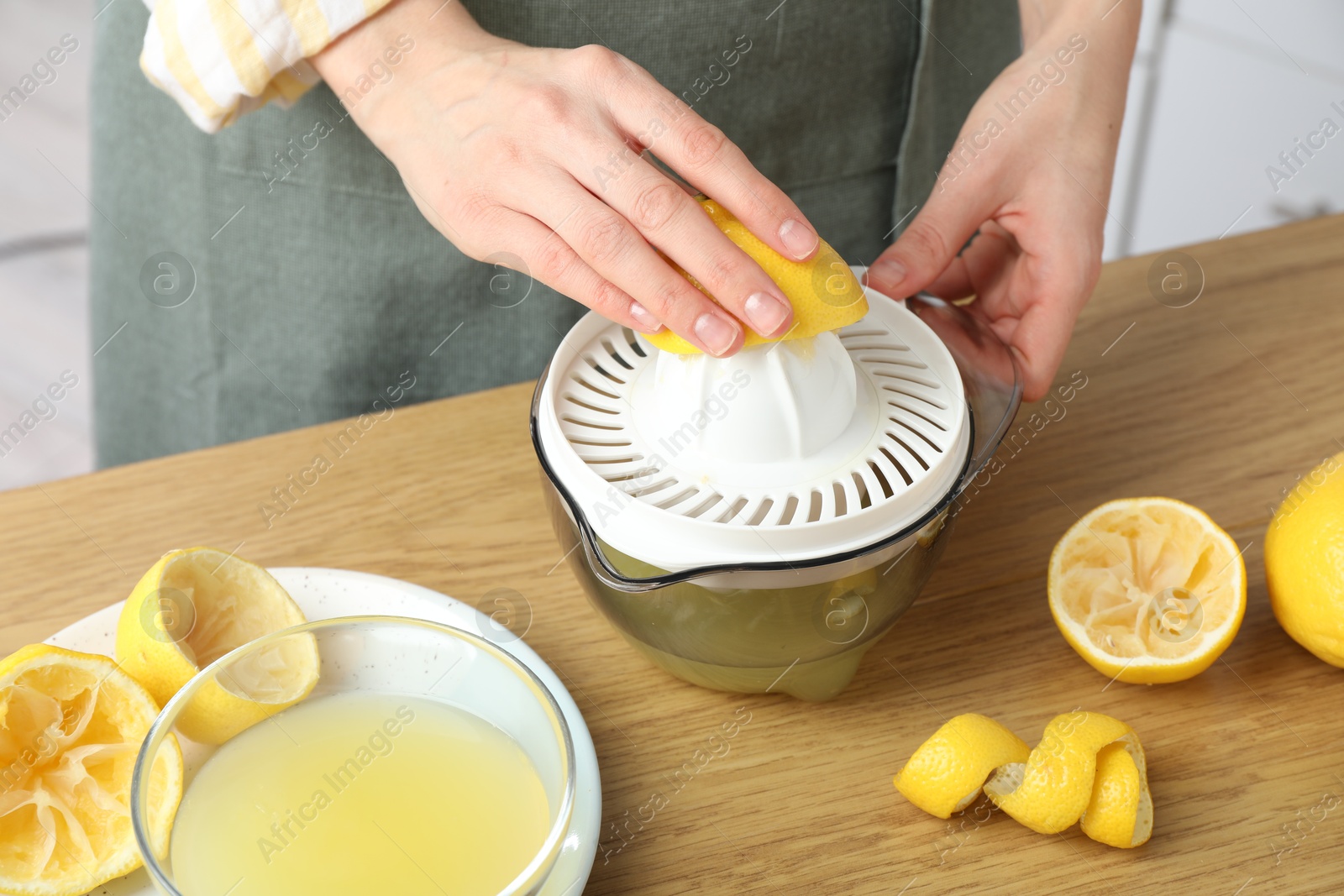 Photo of Woman with lemon using juicer at wooden table, closeup