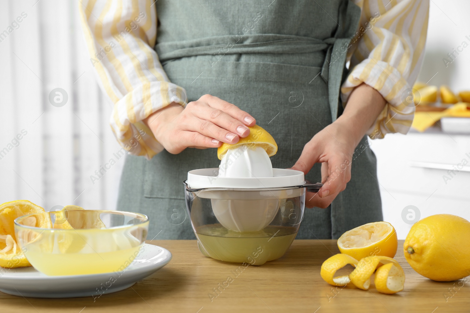 Photo of Woman with lemon using juicer at wooden table, closeup