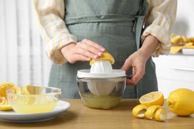 Photo of Woman with lemon using juicer at wooden table, closeup