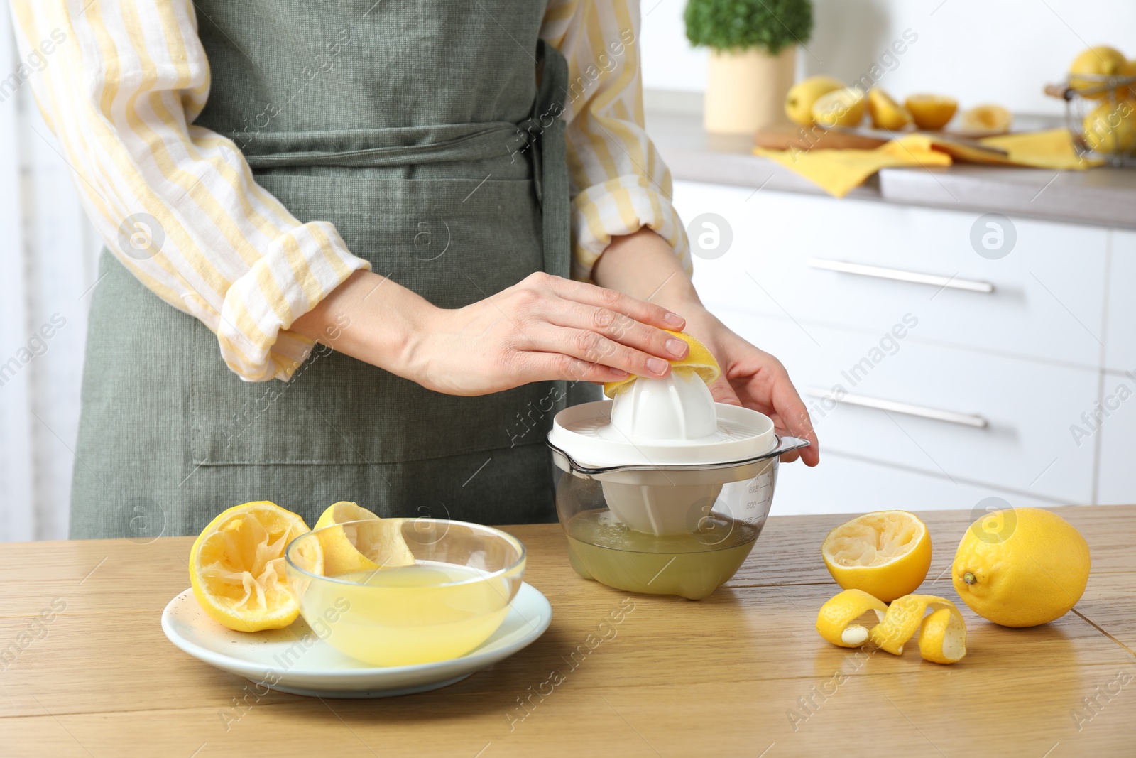 Photo of Woman with lemon using juicer at wooden table, closeup