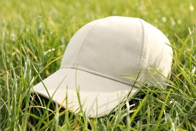 Photo of Stylish baseball cap on green grass, closeup. Mockup for design