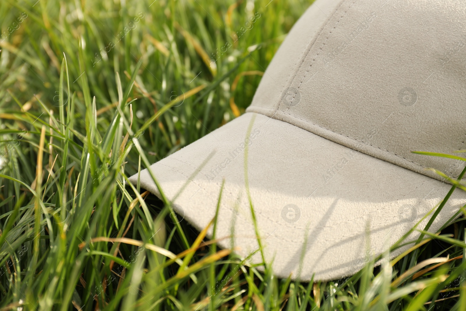 Photo of Stylish baseball cap on green grass, closeup. Mockup for design