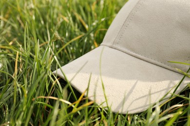 Photo of Stylish baseball cap on green grass, closeup. Mockup for design