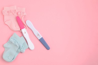 Photo of Pregnancy tests and socks on pink background, top view. Space for text