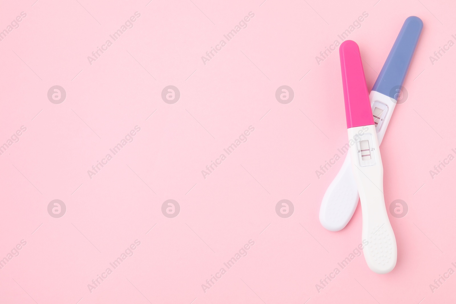 Photo of Pregnancy tests on pink background, above view. Space for text