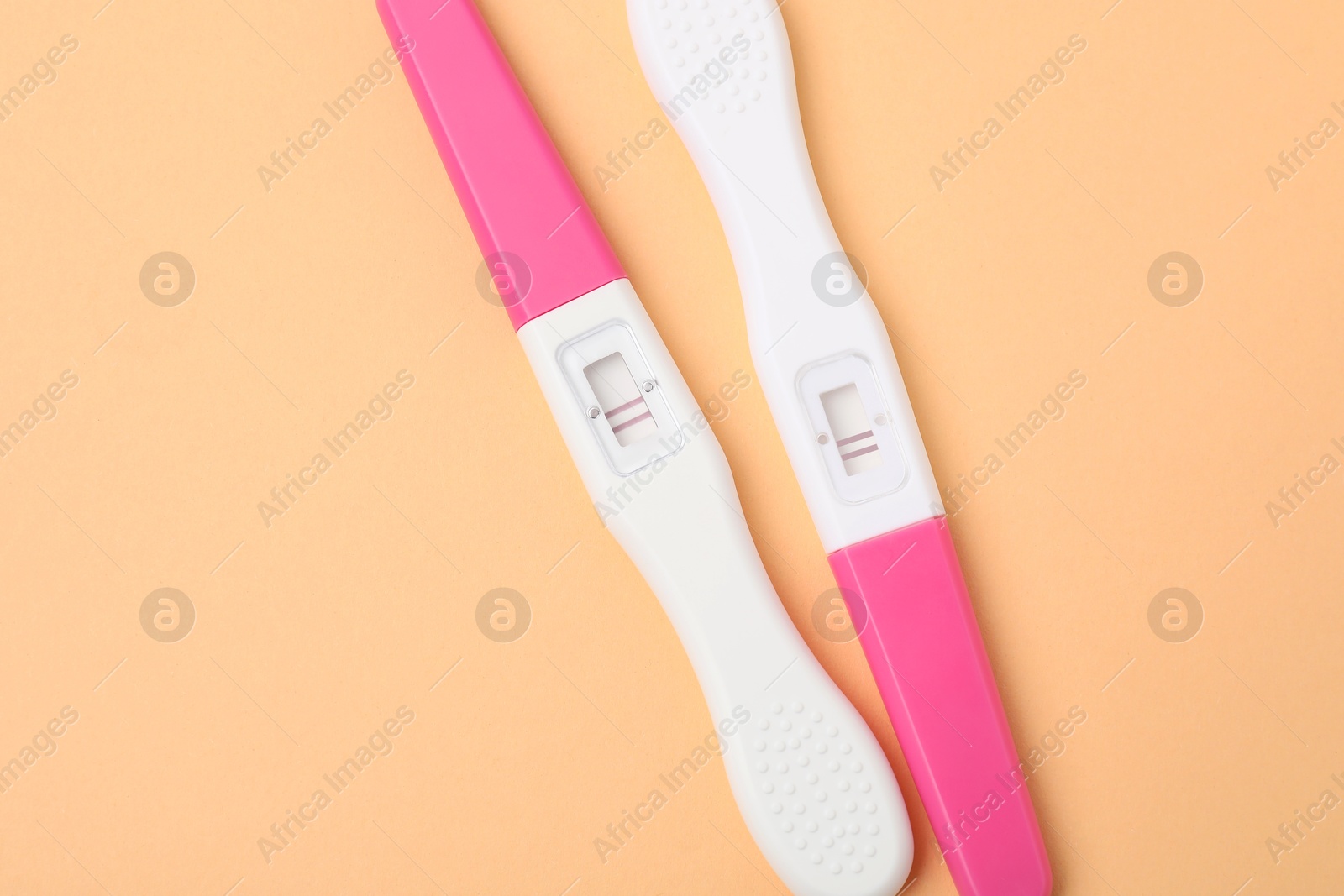 Photo of Pregnancy tests on pale orange background, top view