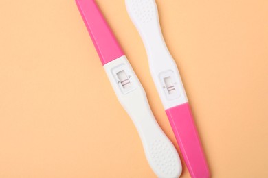 Photo of Pregnancy tests on pale orange background, top view