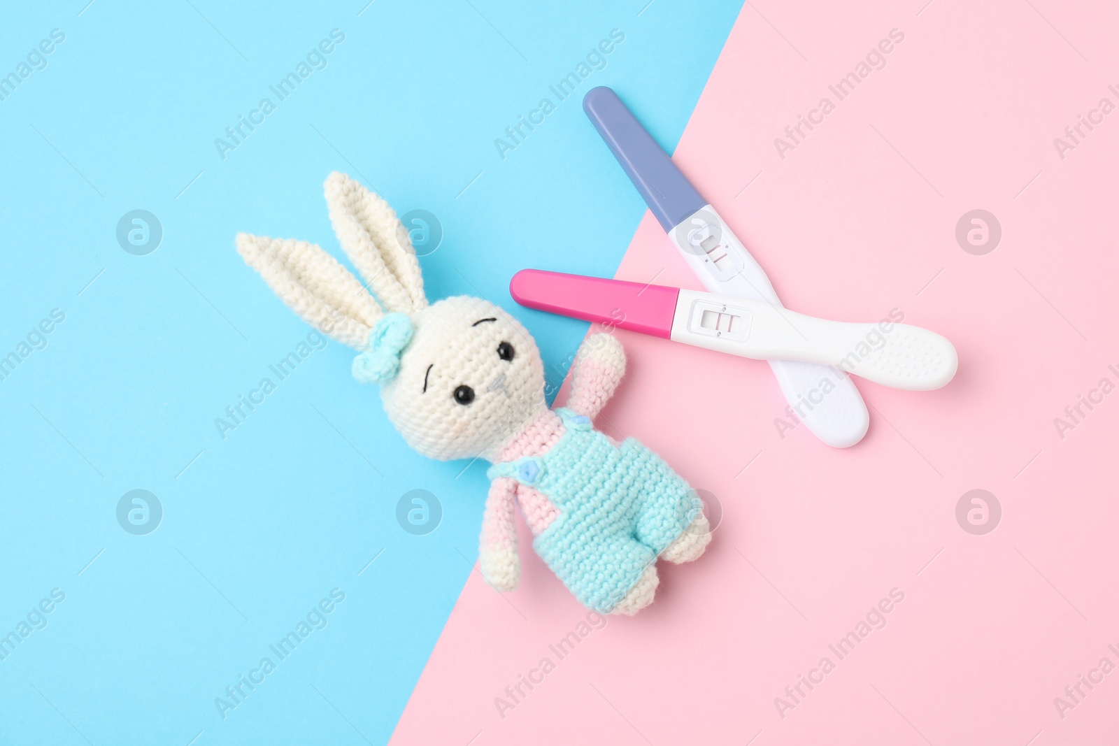 Photo of Two pregnancy tests and bunny toy on color background, flat lay