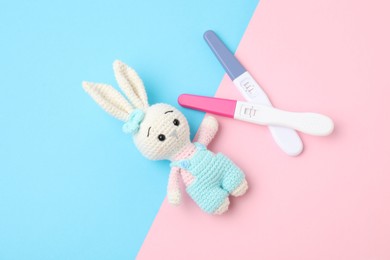 Photo of Two pregnancy tests and bunny toy on color background, flat lay