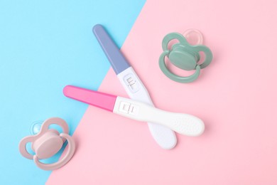 Photo of Pregnancy test and baby pacifiers on color background, flat lay