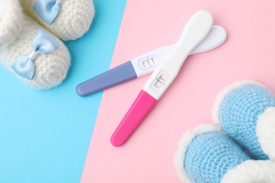 Photo of Pregnancy test and baby shoes on color background, flat lay