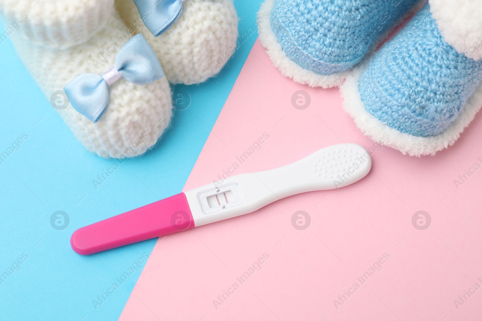 Photo of Pregnancy test and baby shoes on color background, above view