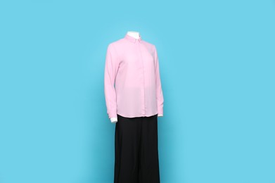 Photo of Female mannequin with stylish shirt and pants on light blue background