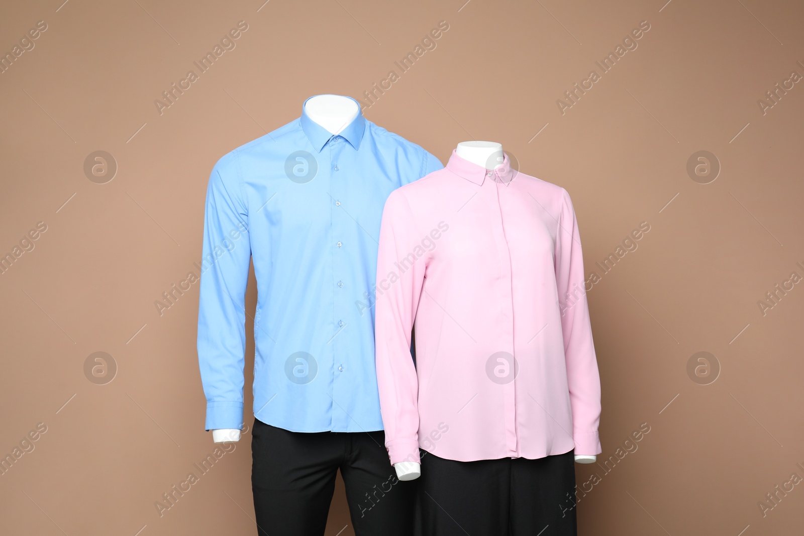 Photo of Female and male mannequins with stylish outfits on light brown background