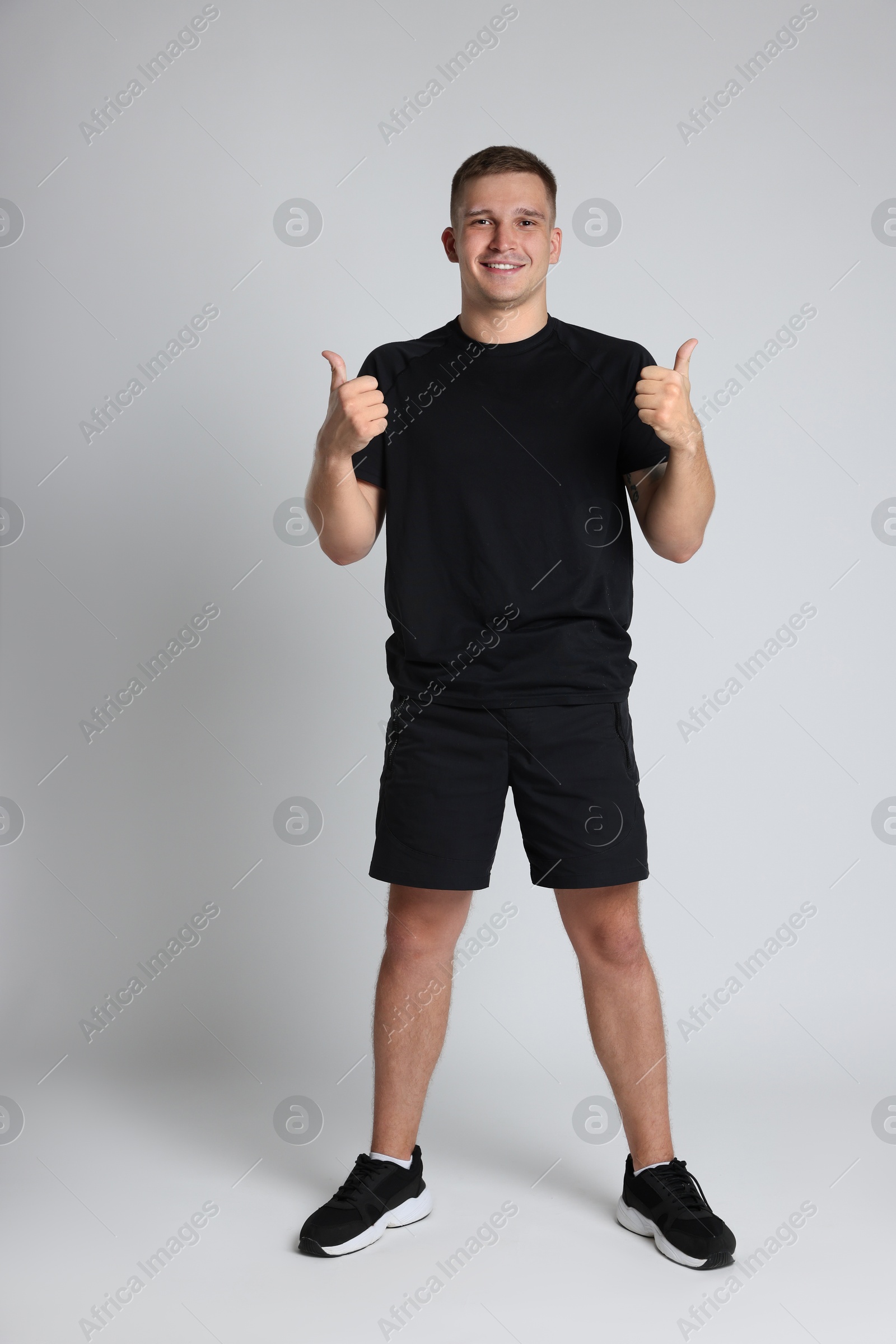 Photo of Happy winner showing thumbs up on light grey background