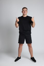 Photo of Happy winner showing thumbs up on light grey background