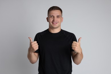 Photo of Happy winner showing thumbs up on light grey background