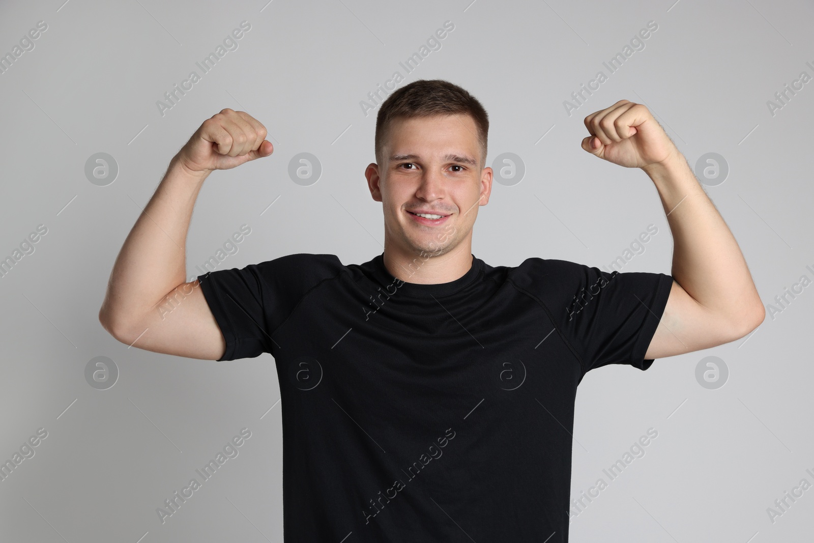 Photo of Happy winner showing his biceps on light grey background