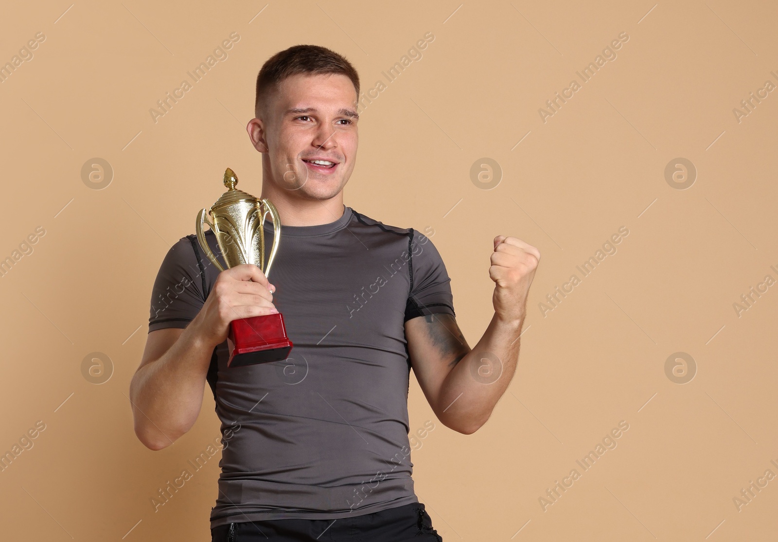 Photo of Happy winner with golden trophy cup on beige background