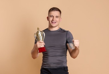 Photo of Happy winner with golden trophy cup on beige background