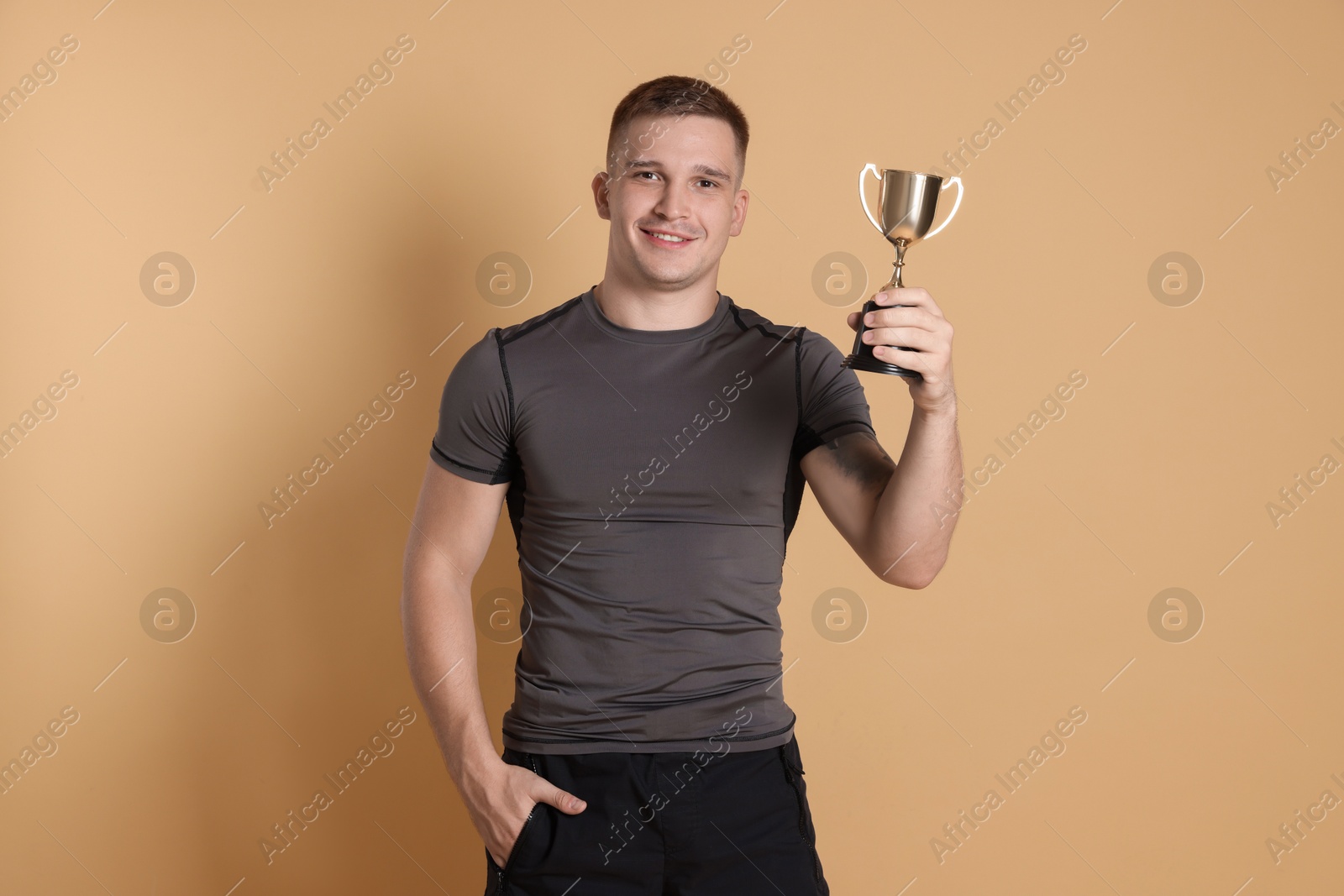 Photo of Happy winner with golden trophy cup on beige background