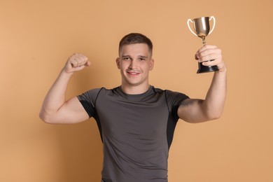 Photo of Happy winner with golden trophy cup on beige background