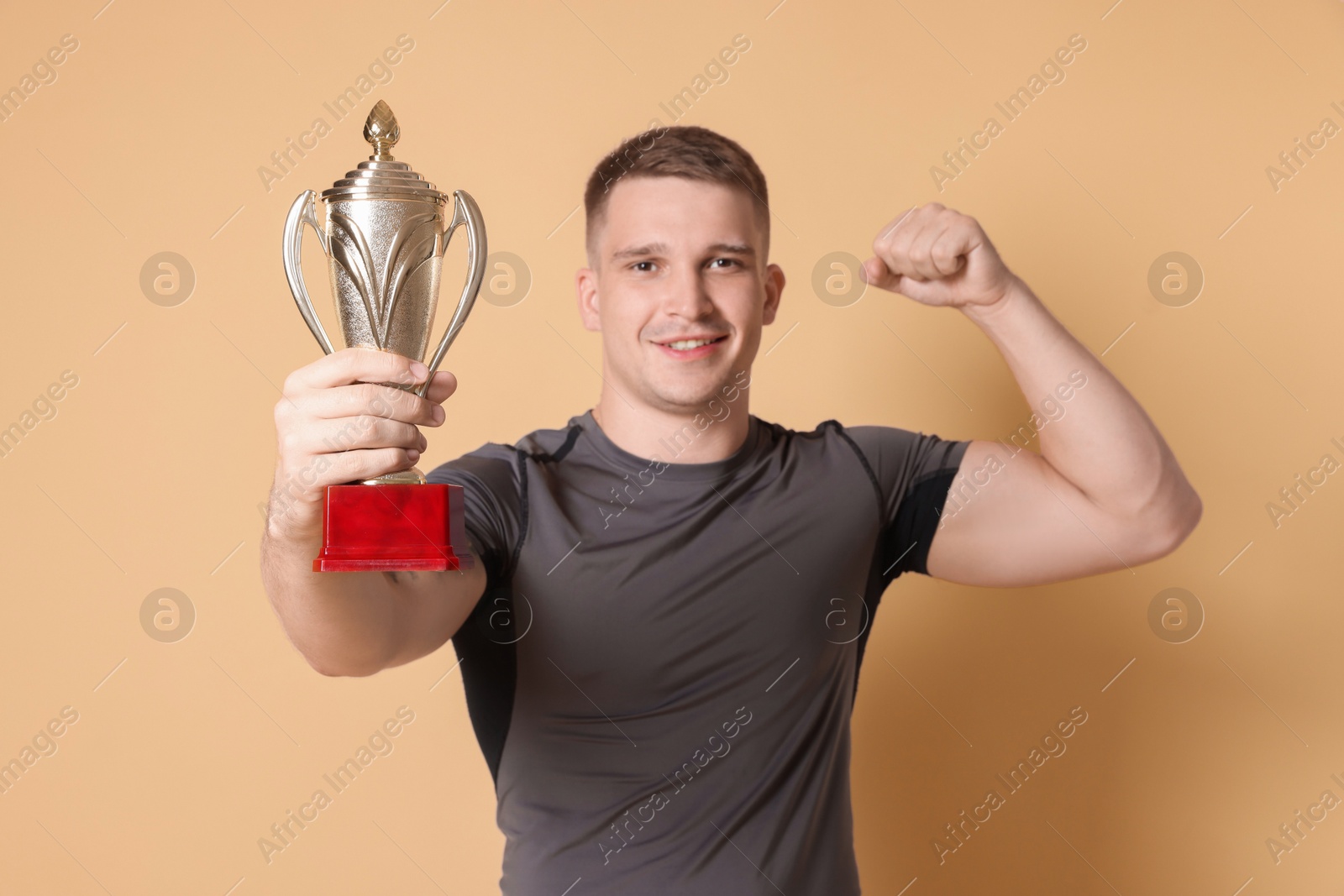 Photo of Happy winner with golden trophy cup on beige background