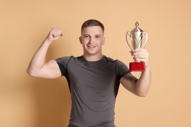 Photo of Happy winner with golden trophy cup on beige background