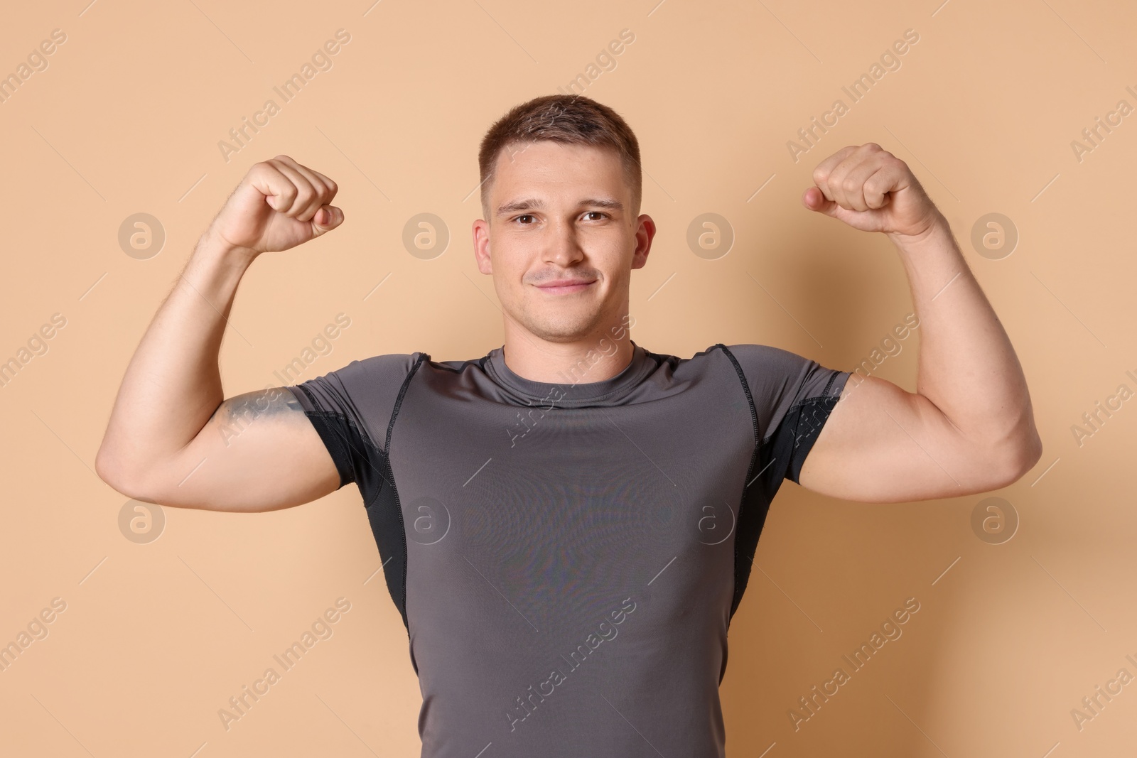 Photo of Smiling winner showing his biceps on beige background