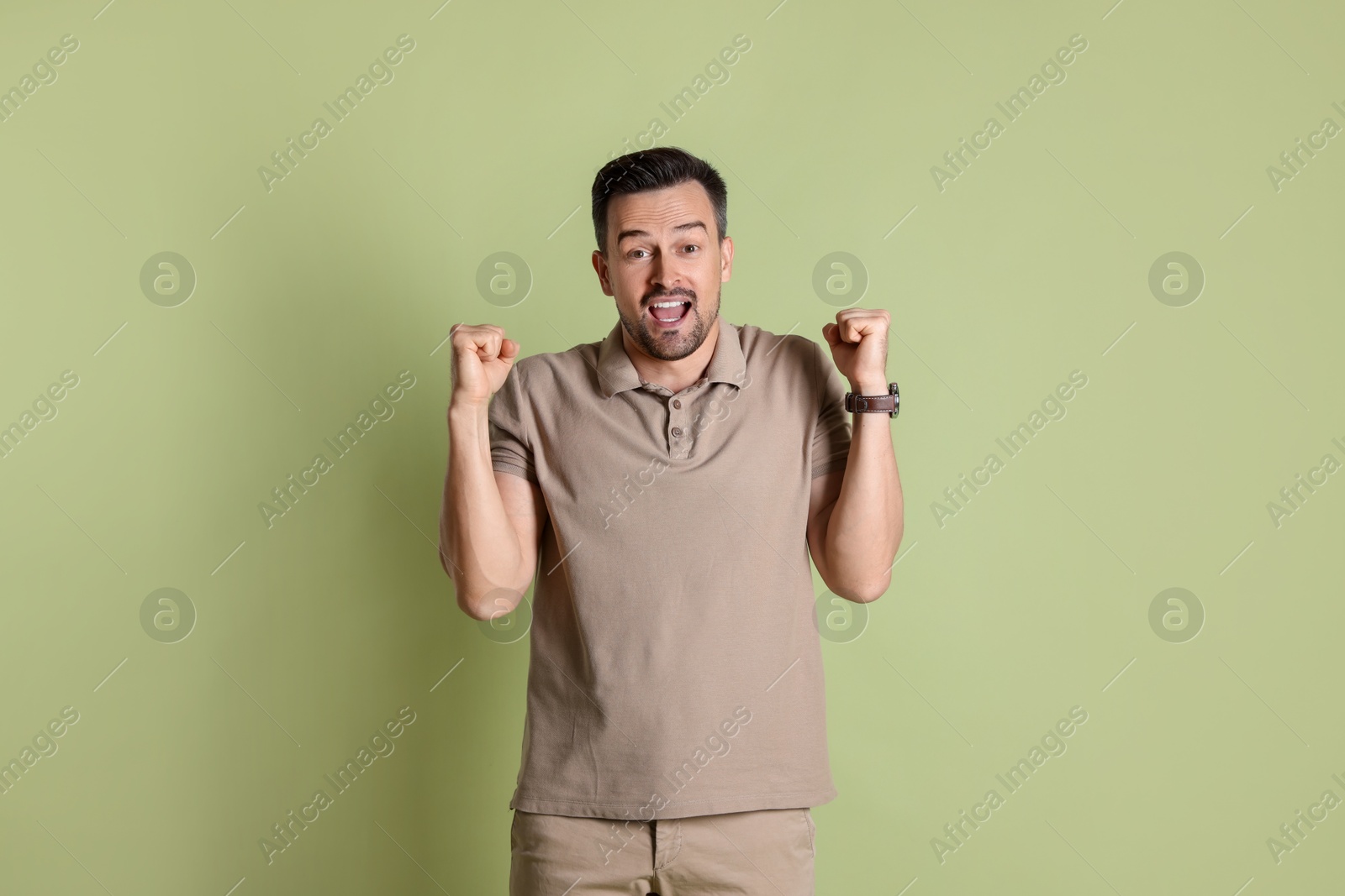 Photo of Portrait of happy winner on pale olive background