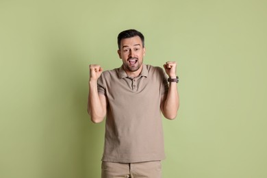 Photo of Portrait of happy winner on pale olive background