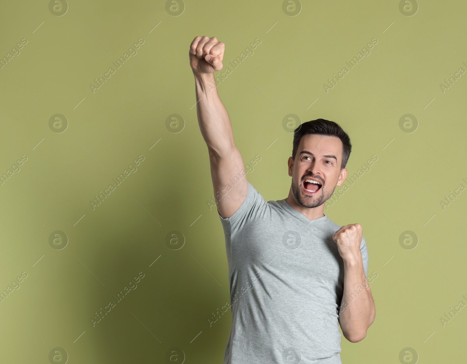 Photo of Portrait of happy winner on pale olive background, space for text