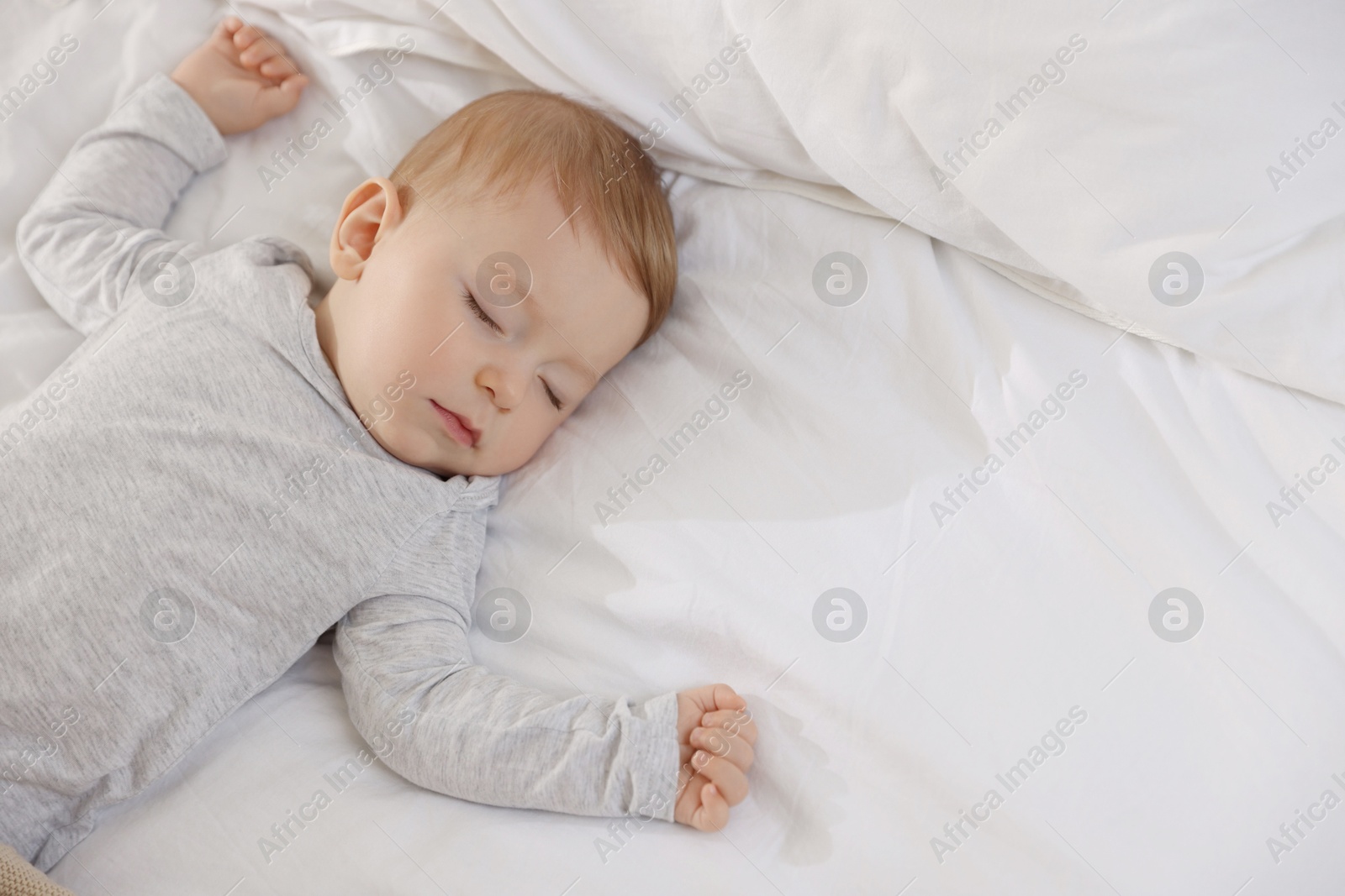 Photo of Cute little baby sleeping on bed at home, space for text