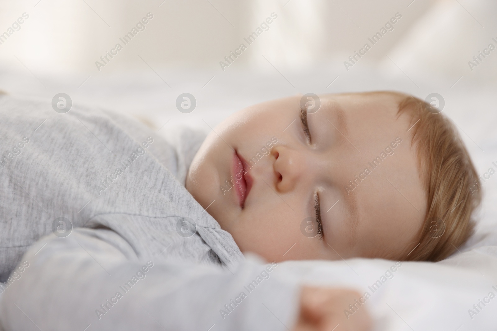 Photo of Cute little baby sleeping on bed at home, closeup