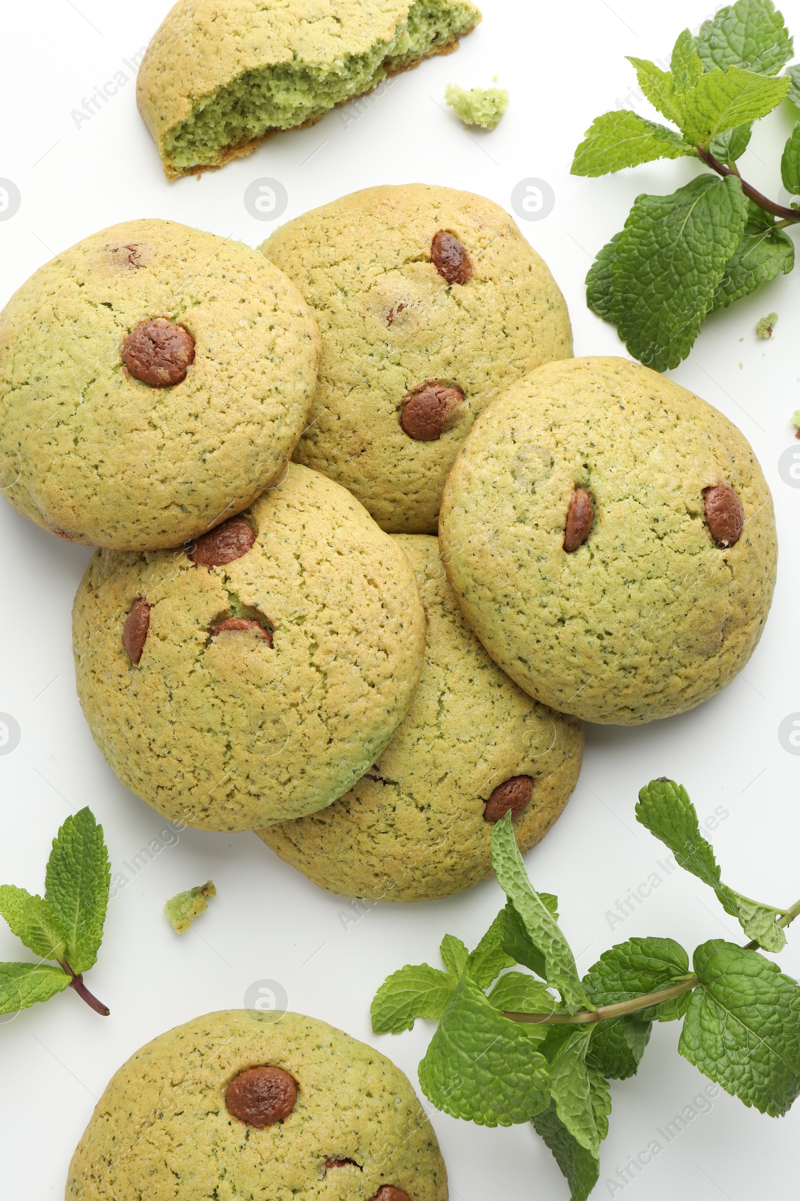 Photo of Delicious chocolate chip cookies and mint leaves on white table, flat lay