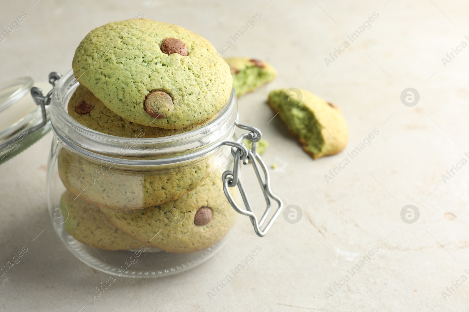 Photo of Delicious mint chocolate chip cookies in jar on light table, closeup. Space for text