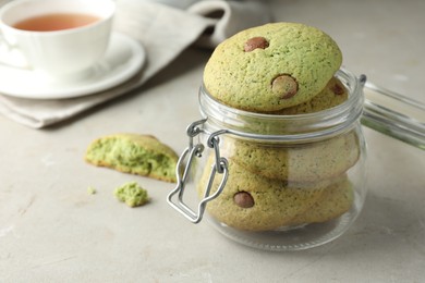 Photo of Delicious mint chocolate chip cookies in jar on light table, closeup