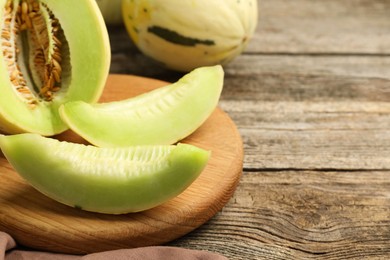 Photo of Fresh cut honeydew melon on wooden table, closeup. Space for text