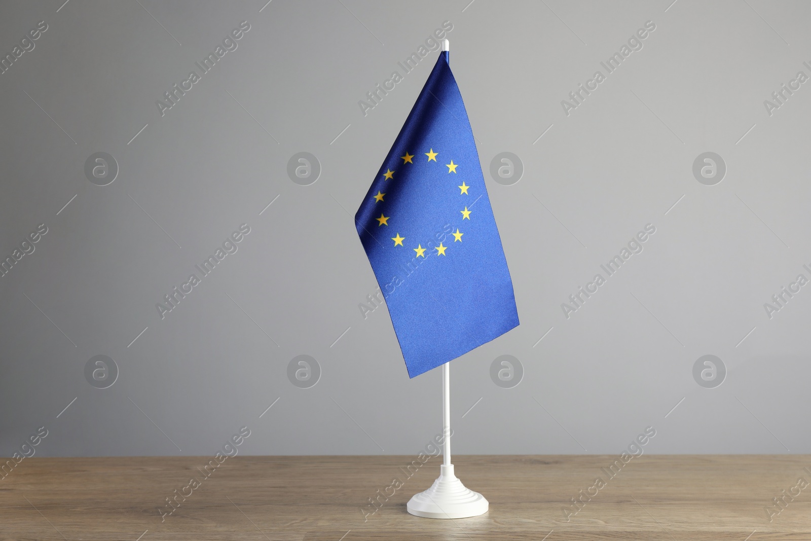 Photo of One flag of European Union on wooden table against grey background