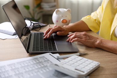 Photo of Budget planning. Woman using laptop at table indoors, closeup