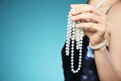 Photo of Young woman with pearl jewelry on blue background, closeup. Space for text