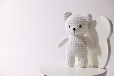 Photo of Cute crocheted bear on wooden chair against white background, space for text