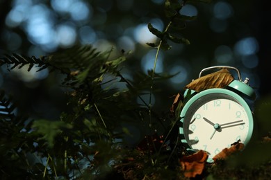 Photo of Alarm clock on green moss outdoors, closeup. Space for text