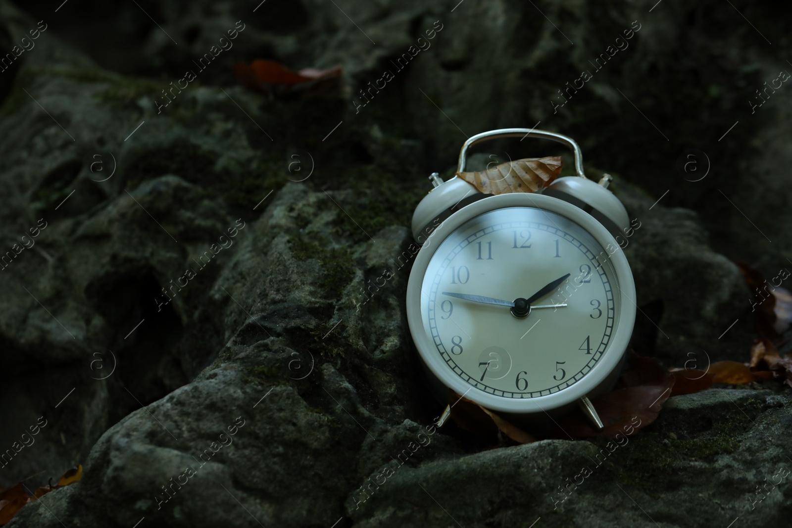 Photo of Alarm clock on stones outdoors, closeup. Space for text