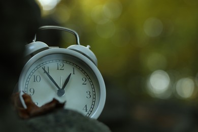 Photo of Alarm clock on stones outdoors, closeup. Space for text