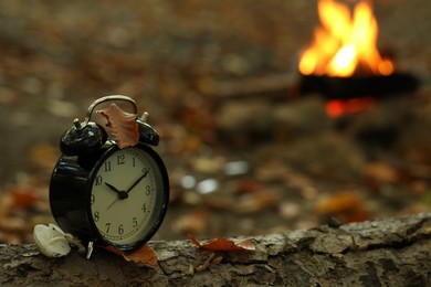 Photo of Alarm clock on fallen dry leaves outdoors, closeup. Space for text