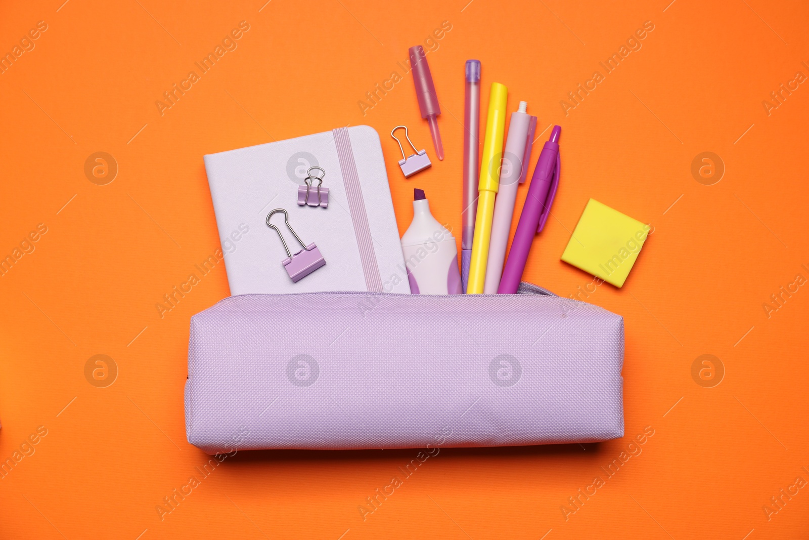 Photo of Pencil case and different stationery on orange background, flat lay