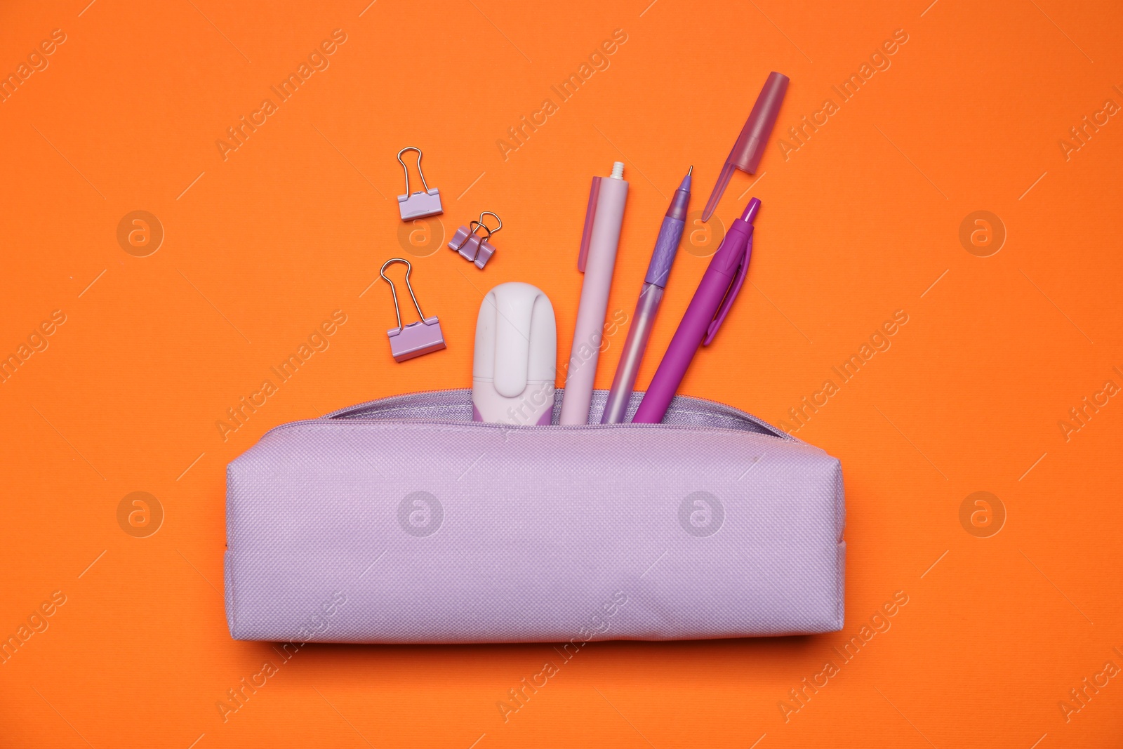 Photo of Pencil case and different stationery on orange background, flat lay