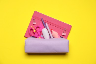 Photo of Pencil case and different stationery on yellow background, flat lay