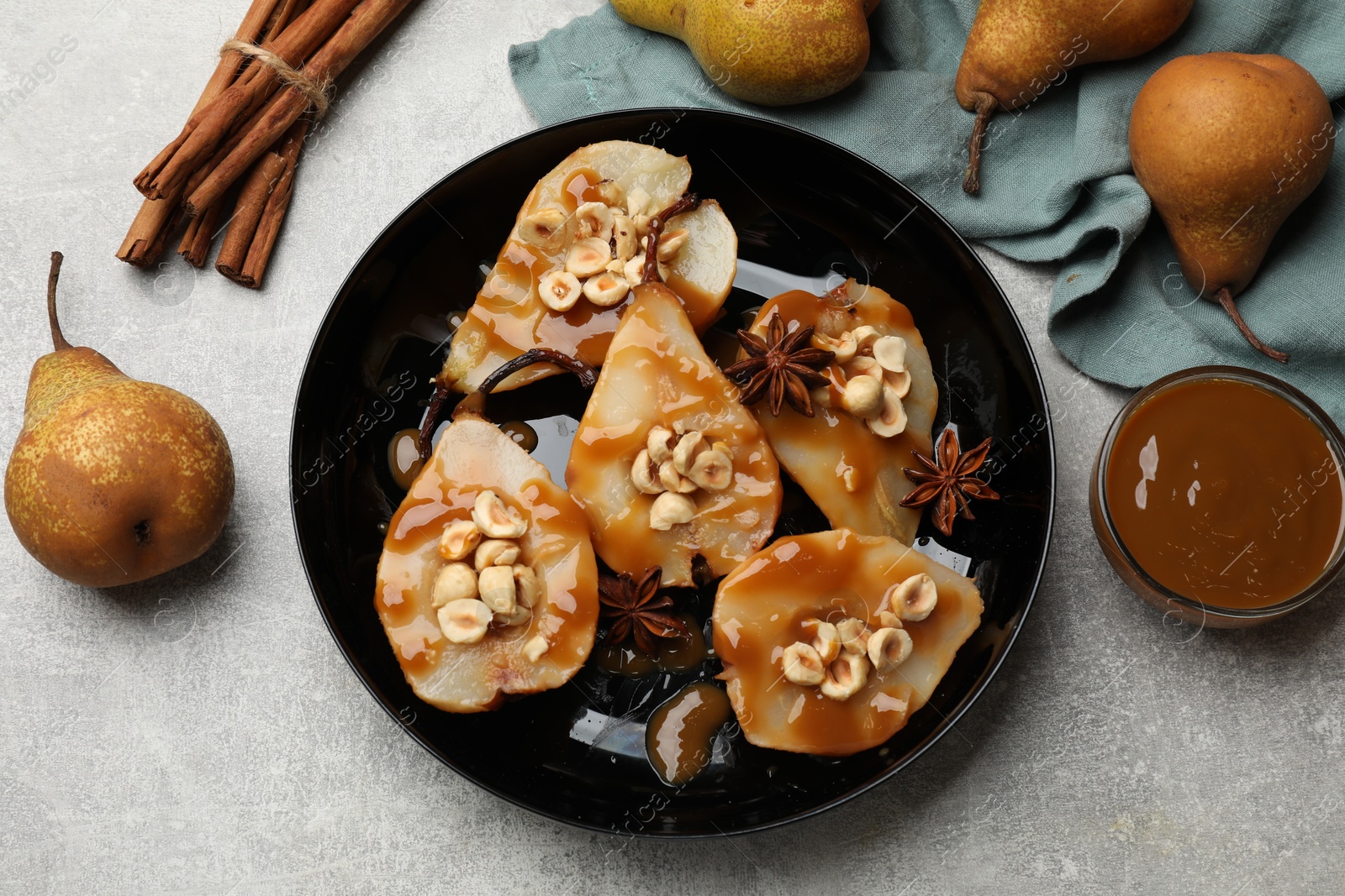 Photo of Delicious pears with caramel sauce, nuts and spices on grey table, top view